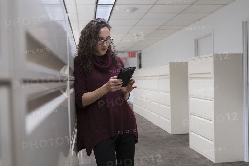 Young woman using digital tablet in corridor.