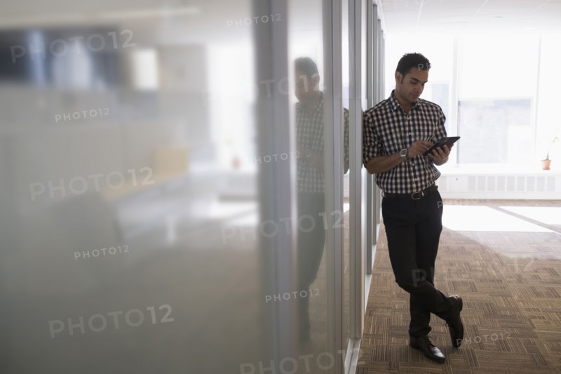 Young man standing in corridor with digital tablet.