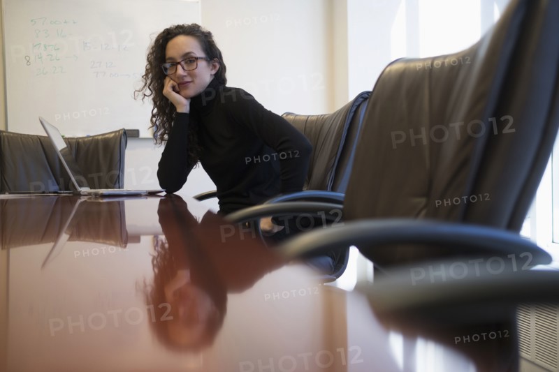 Portrait of young business woman sitting in conference room with laptop.