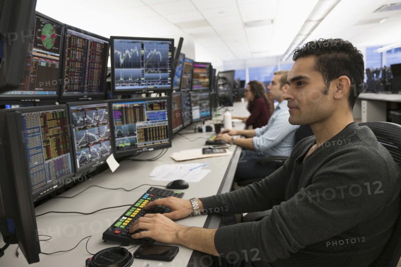 Young traders analyzing computer data.