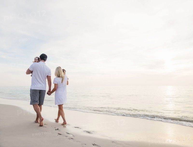 Couple with twins (2-5 months) walking along seashore