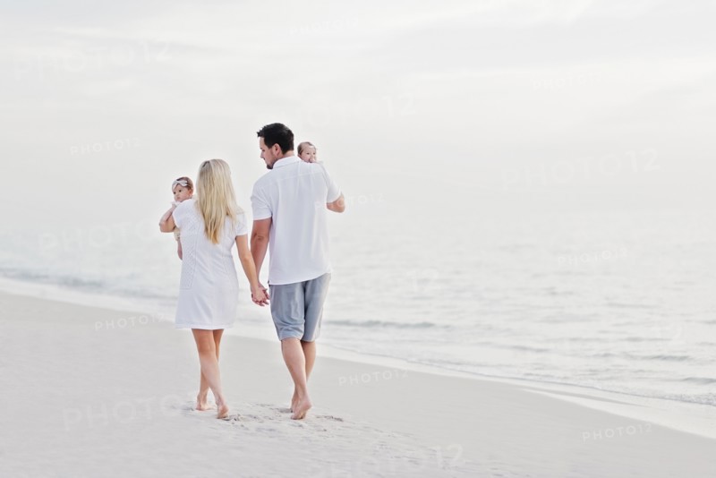 Parents walking with babies (2-5 months) along seashore