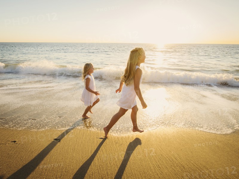 Girls (6-7, 8-9) running on beach