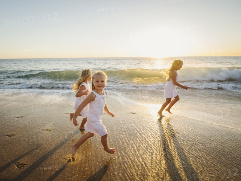 Girls (4-5, 6-7, 8-9) running on beach