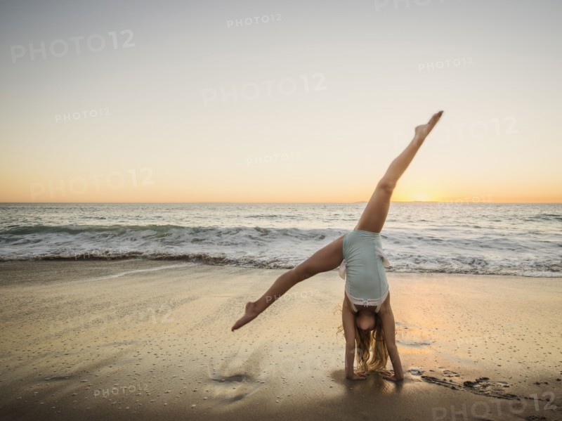 Girl (8-9) doing cartwheel on beach