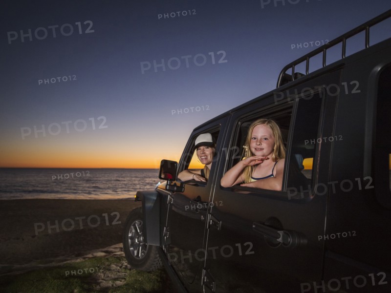Mother and daughter (4-5) sitting in car on beach
