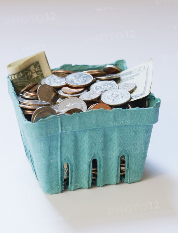 Coins and banknotes in carton box on on white surface