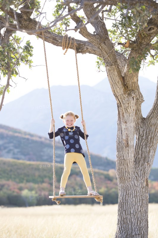 Girl (4-5) standing on swing