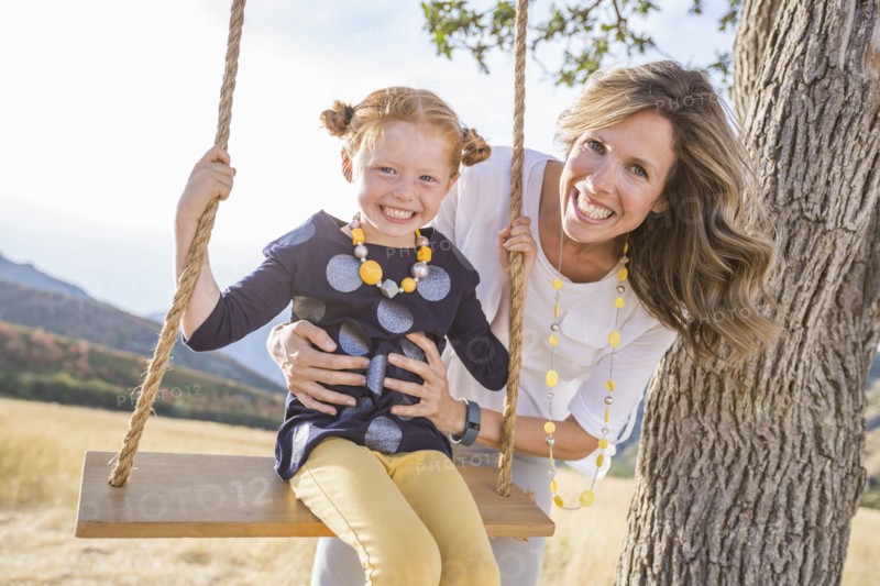 Mother with girl (4-5) sitting on swing