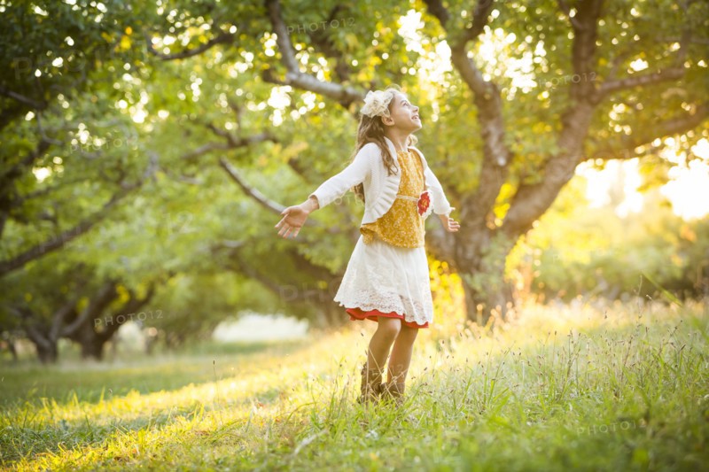 Carefree girl spinning in orchard with outstretched arms