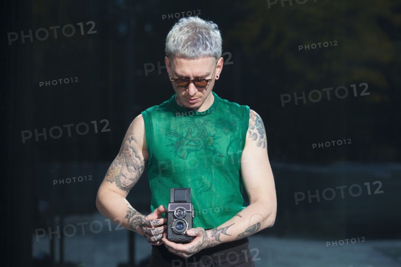 Tattooed man holding vintage camera