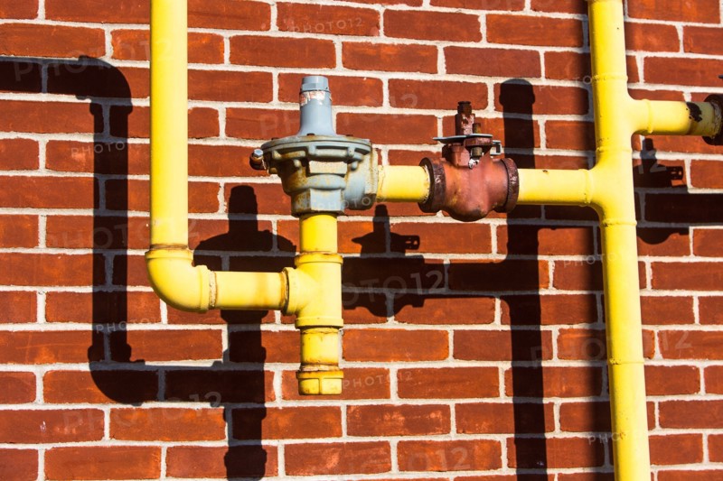 Close up of pipes in front of brick wall