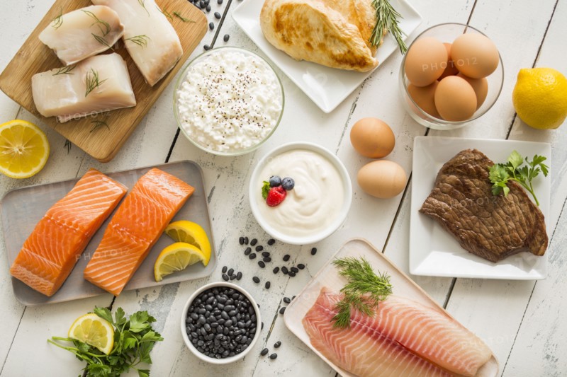 Chicken meat, fish, cottage cheese, yogurt and eggs on white table