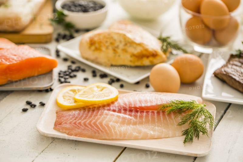 Raw tilapia fish on plate, chicken and eggs in background