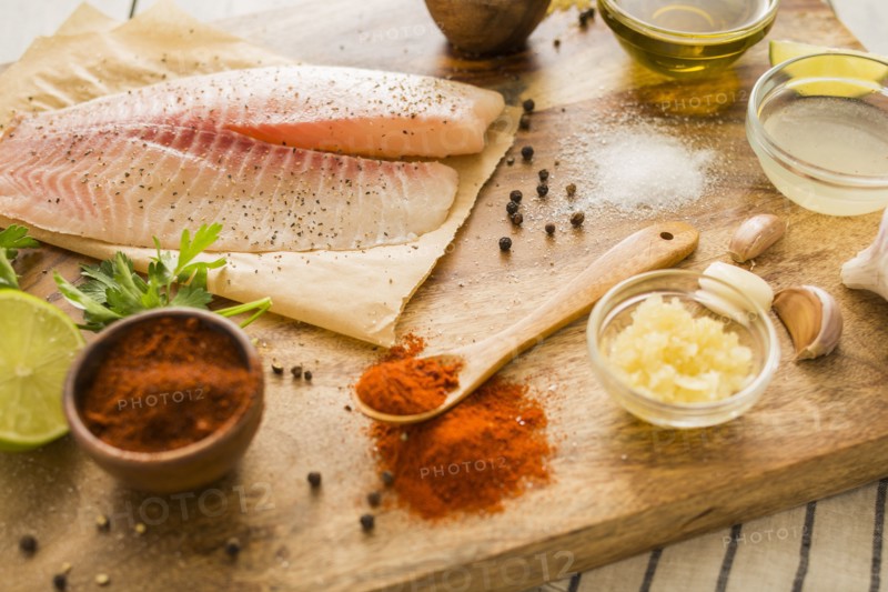 Raw tilapia and ingredients on cutting board