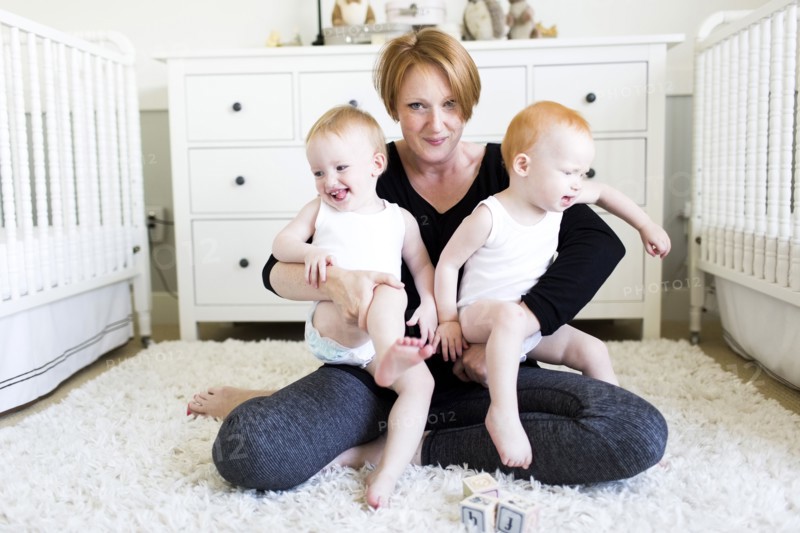 Portrait of mother holding sons (12-17 months) in nursery