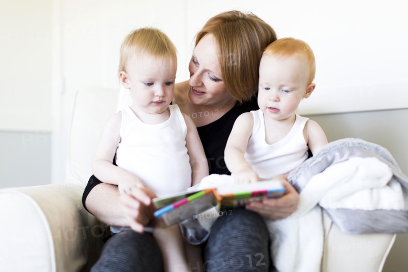 Mother and sons (12-17 months) reading picture book