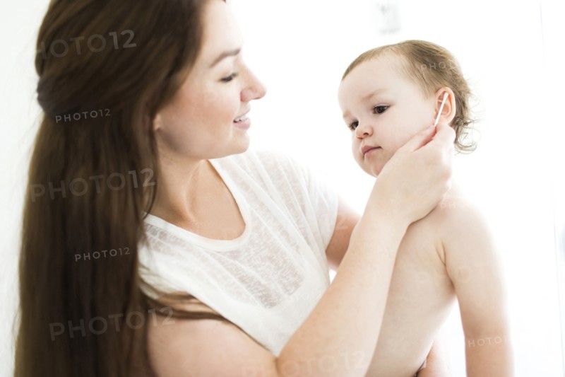 Mother cleaning son (4-5) ear