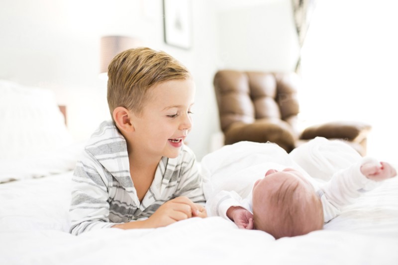 Brother (4-5) and sister (0-1 months) lying on bed