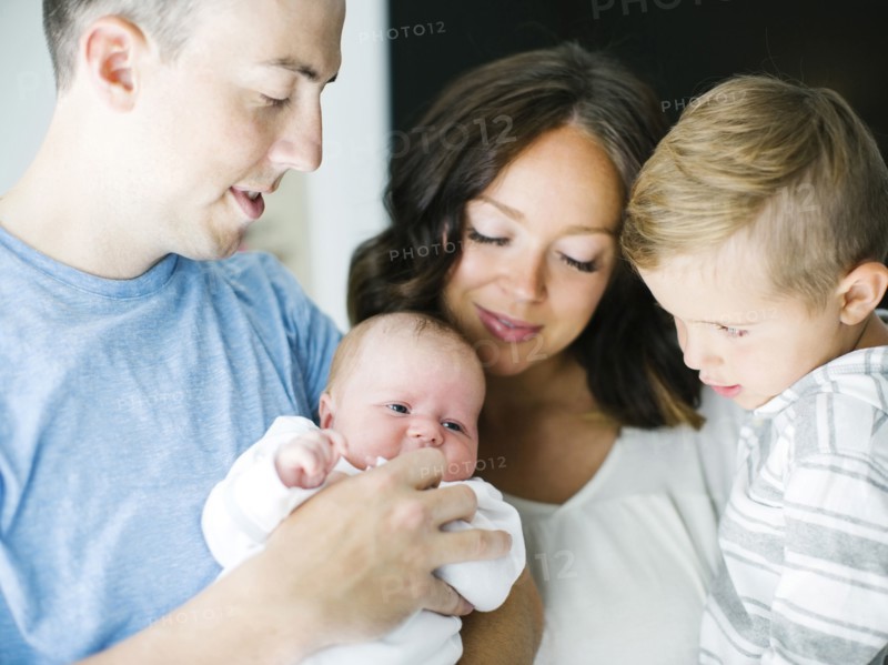 Mother and father carrying son (4-5) and daughter (0-1 months)