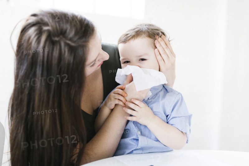 Young boy (4-5) blowing nose