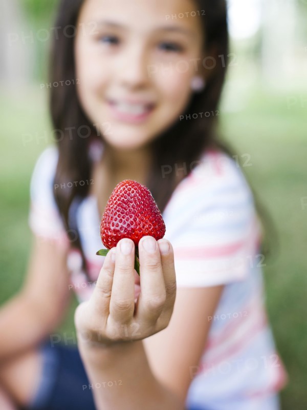 Girl (10-11) presenting strawberry