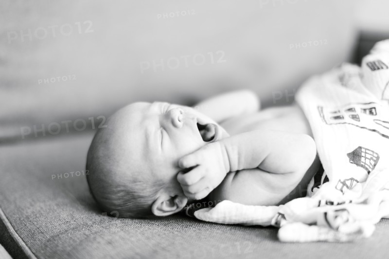 Baby boy (0-1 months) lying on back and yawning