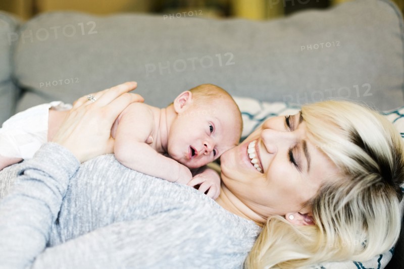 Mother lying on sofa and holding  his one day son (0-1 months)