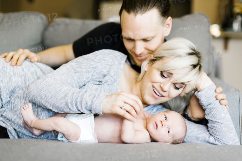 Family with one day son (0-1 months) lying on sofa