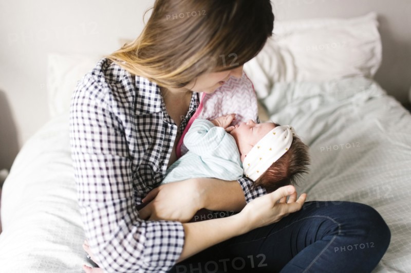 Young mother with baby girl (0-1 months) sitting in bedroom