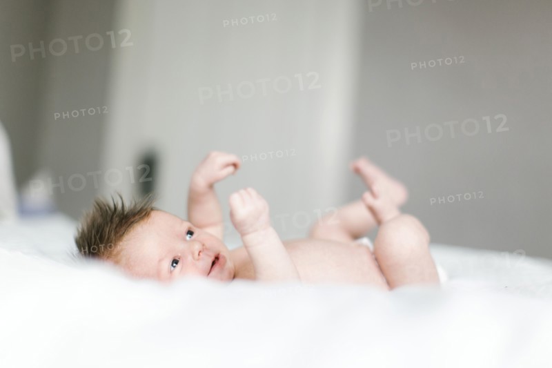 Naked baby girl (0-1 months) lying on bed