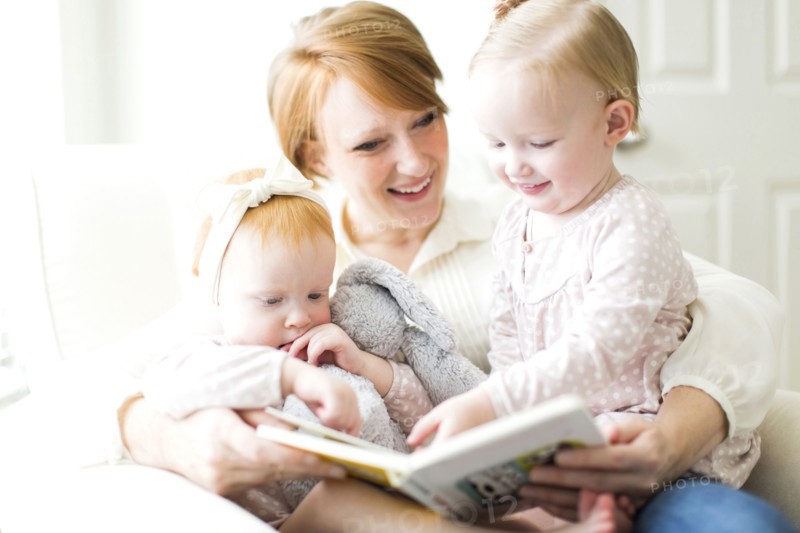 Mother reading book to daughters ( 12-17 months )