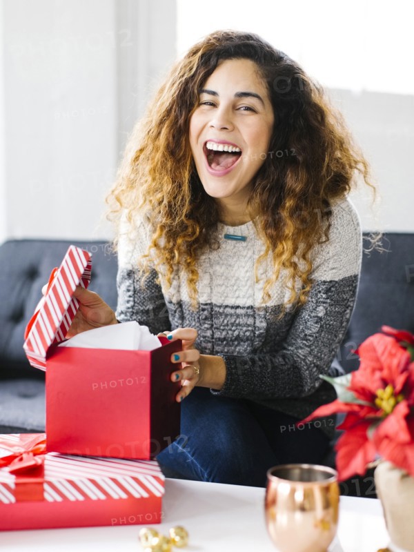Happy woman on sofa opening Christmas gift