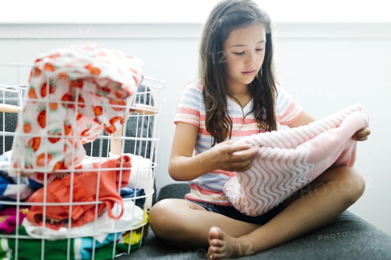 Girl (10-11) folding laundry