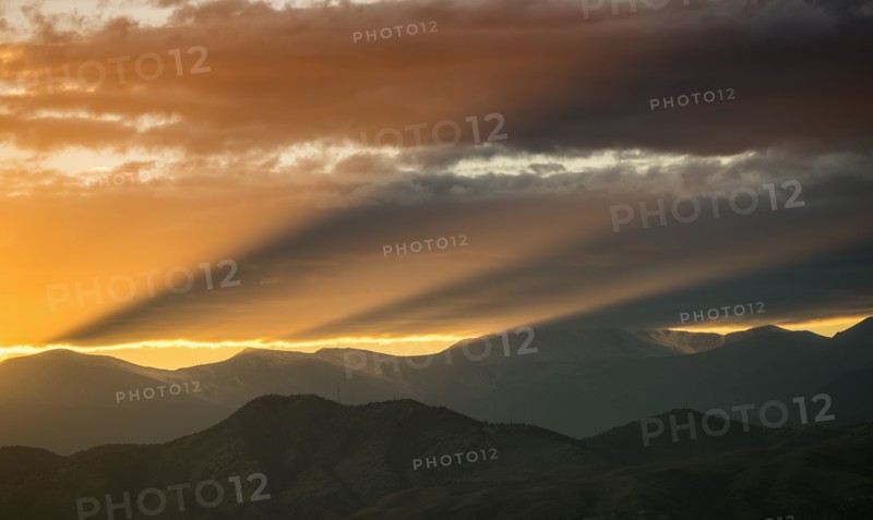 USA, Colorado, Denver, Setting sun shining through clouds over Front Range
