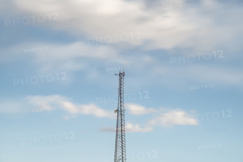 Top of communications tower with sky and clouds in background