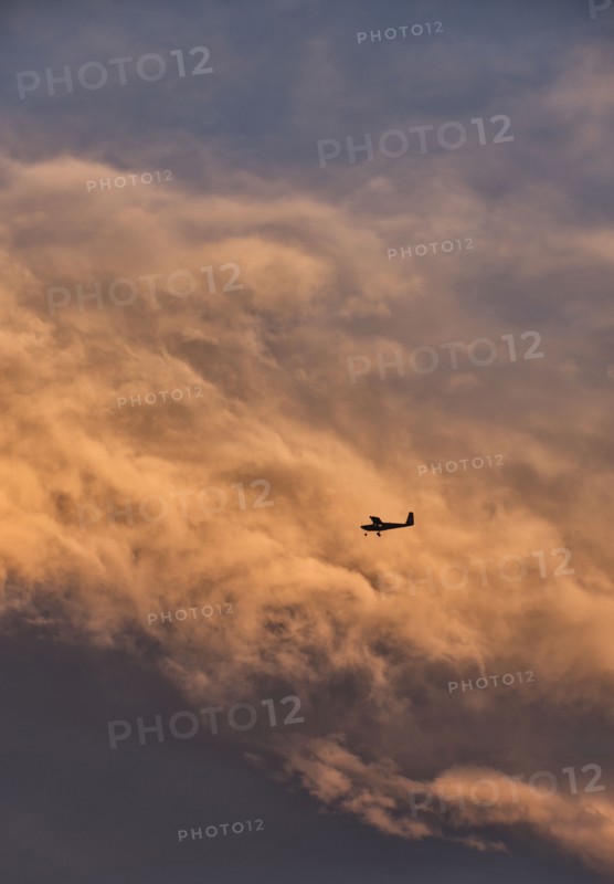 Small plane in sky with clouds in background