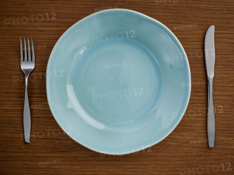 Studio shot of blue plate with fork and knife