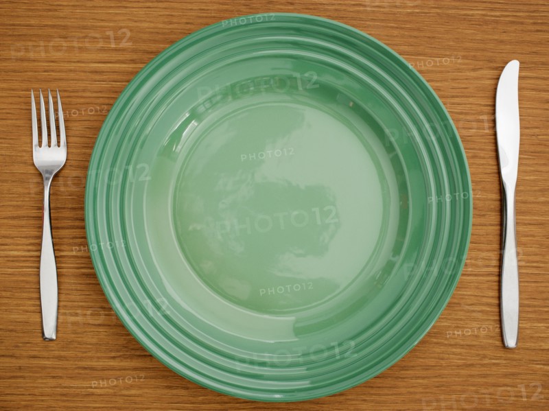 Studio shot of green plate with fork and knife