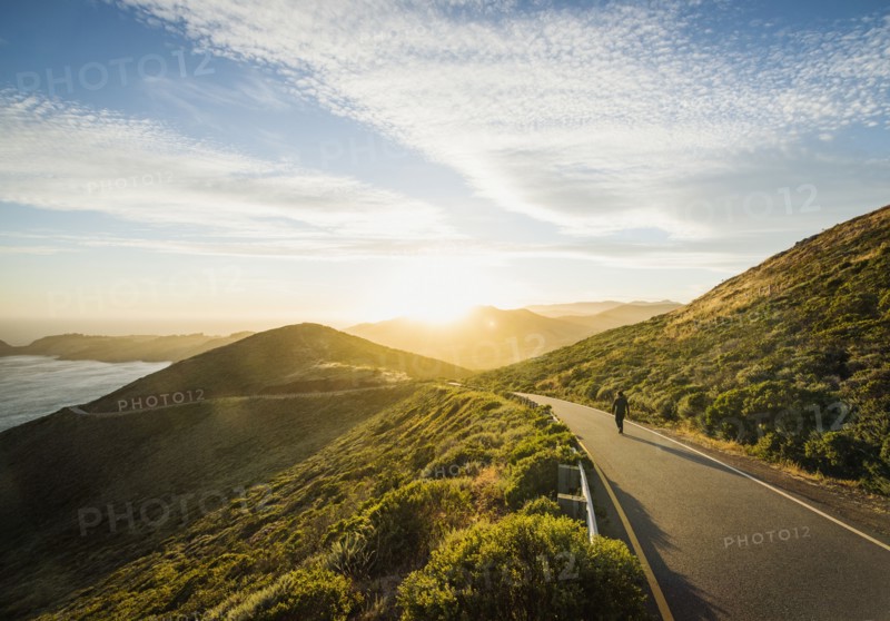 USA, California, San Francisco, California, Man walking on coastline road at sunset