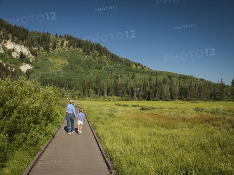 USA, Utah, Lake City, Girl (4-5) with grandmother walking on boardwalk through wetland