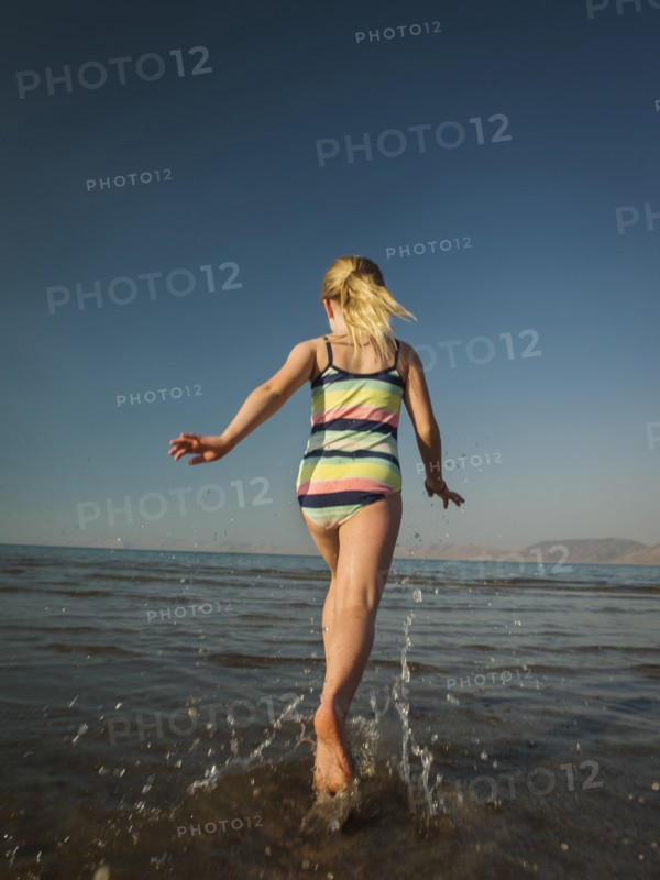 Girl (4-5) running into lake