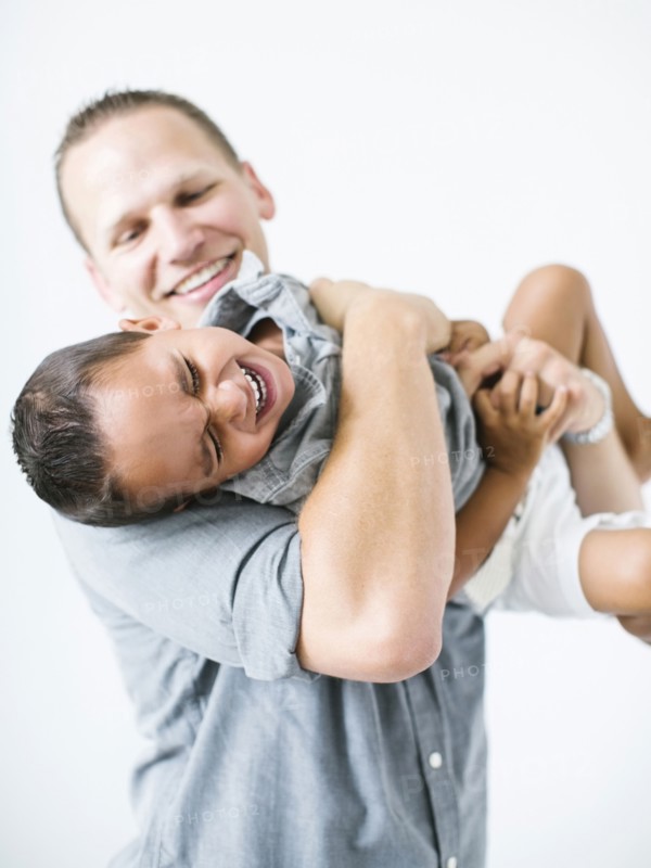 Father holding son (2-3) and laughing