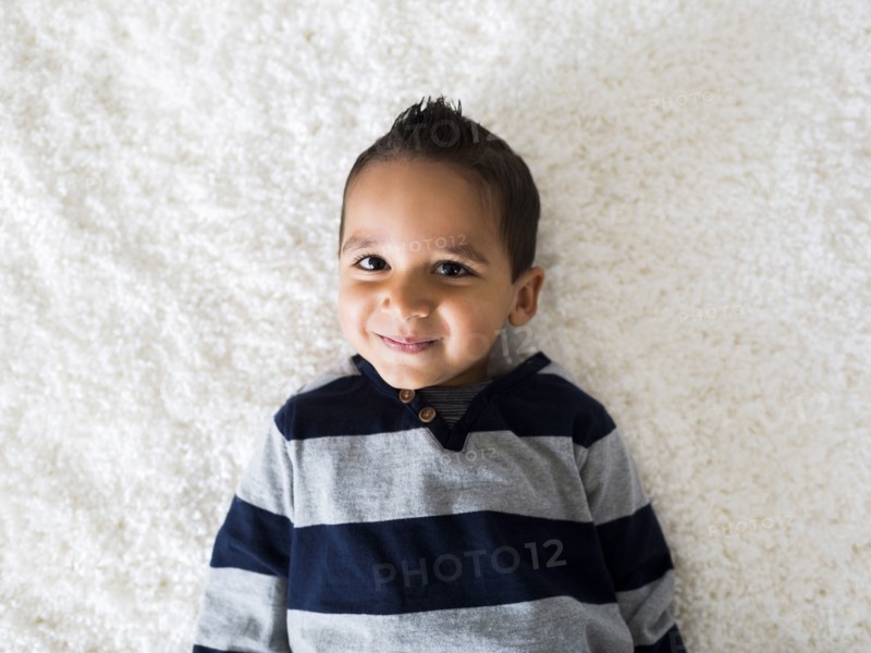 Boy (2-3) lying down on carpet