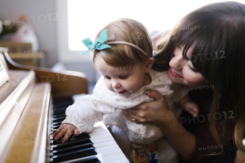 Mother with daughter (12-17 months) playing piano
