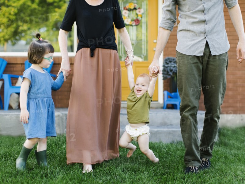 Parents with daughters (2-3, 12-17 months) standing on grass