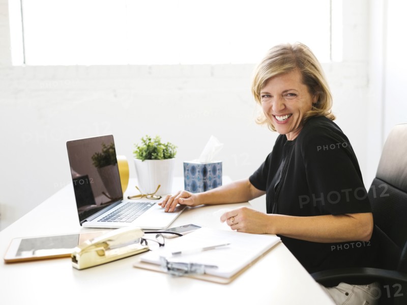 Woman using laptop, looking at camera