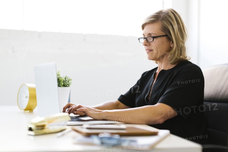 Mature woman in office typing on laptop