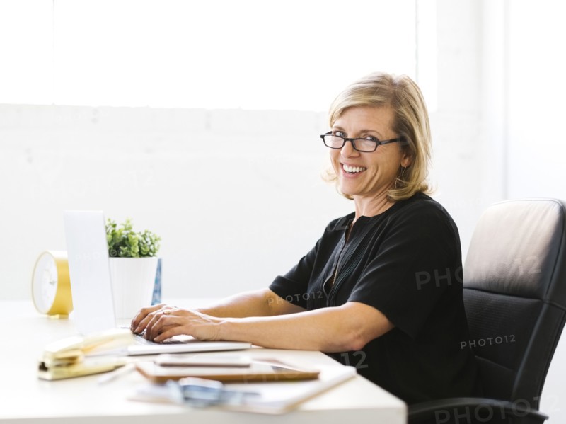 Portrait of Mature woman in office typing on laptop