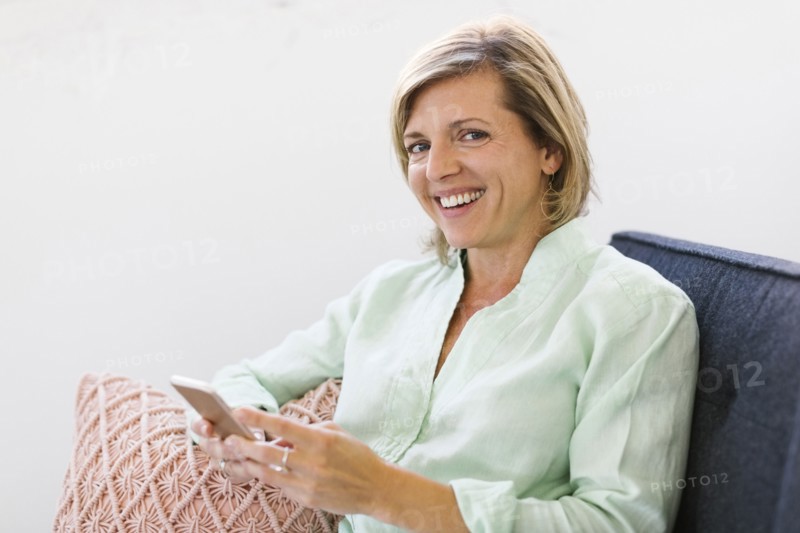Woman holding smart phone on sofa